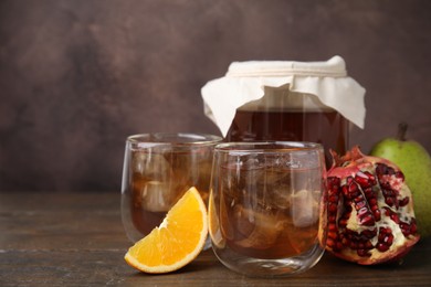 Photo of Tasty kombucha with ice cubes and fruits on wooden table