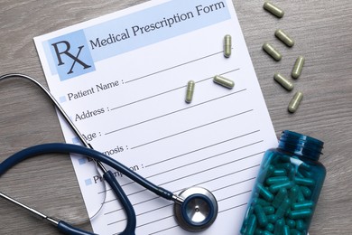 Photo of Medical prescription form, stethoscope and pills on wooden table, flat lay