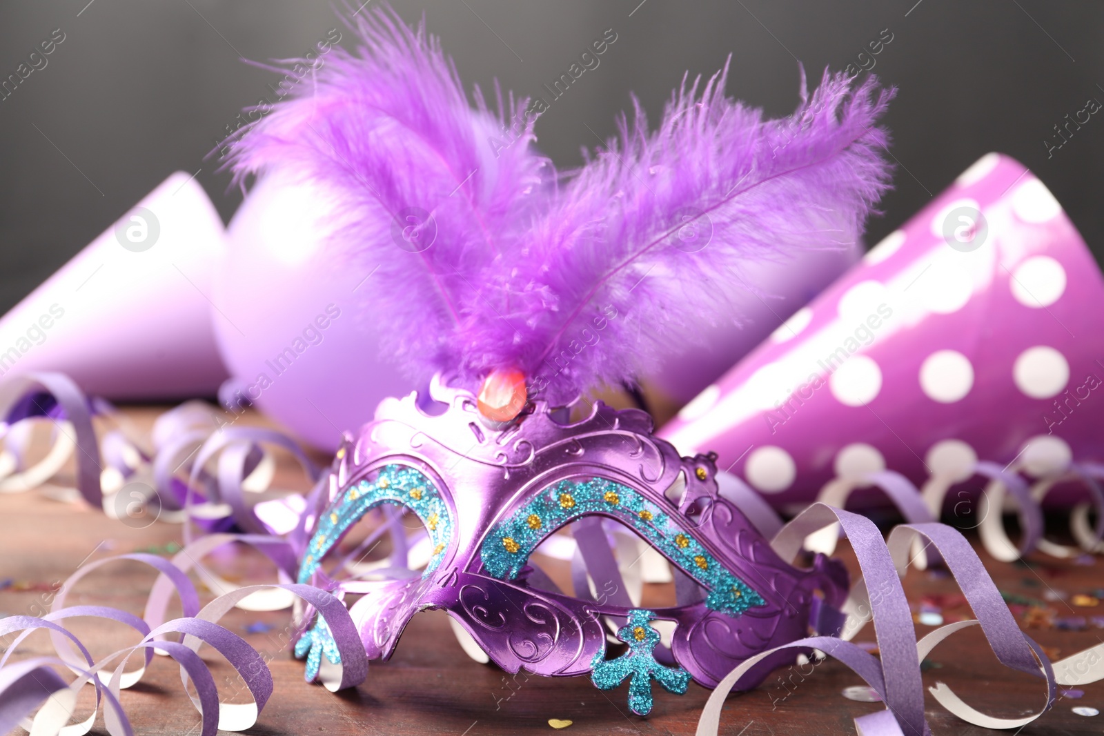 Photo of Beautiful purple carnival mask and  decor on wooden table, closeup