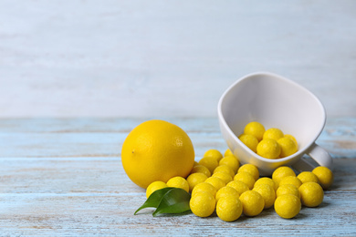 Photo of Fresh lemon and tasty chewing gums on light blue wooden table