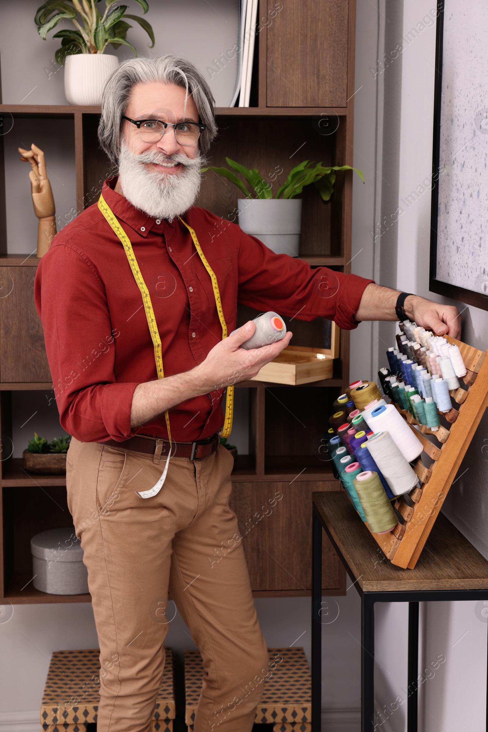 Photo of Professional tailor choosing thread near stand in workshop