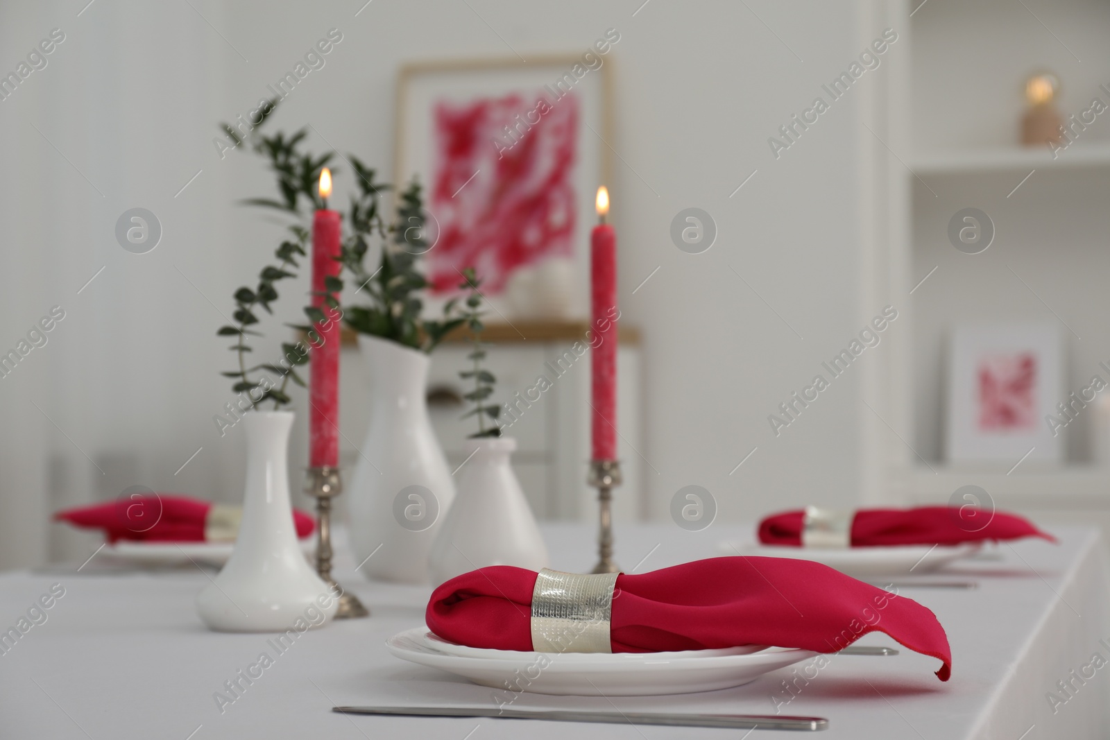 Photo of Beautiful table setting with green branches in vases and burning candles indoors. Stylish dining room