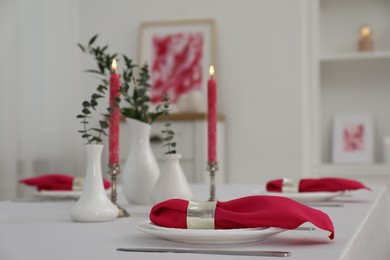 Photo of Beautiful table setting with green branches in vases and burning candles indoors. Stylish dining room