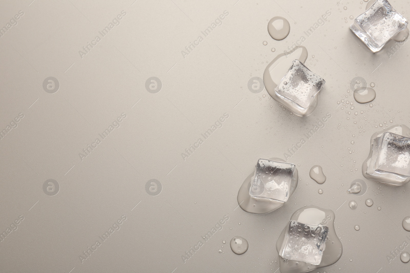 Photo of Melting ice cubes and water drops on light grey background, flat lay. Space for text