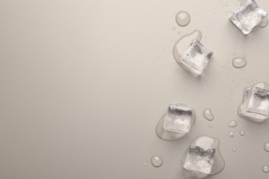 Melting ice cubes and water drops on light grey background, flat lay. Space for text