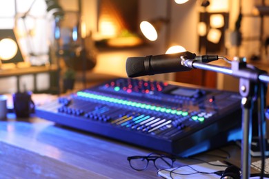 Photo of Microphone near table with professional mixing console in radio studio