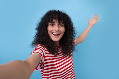 Photo of Beautiful young woman taking selfie on light blue background