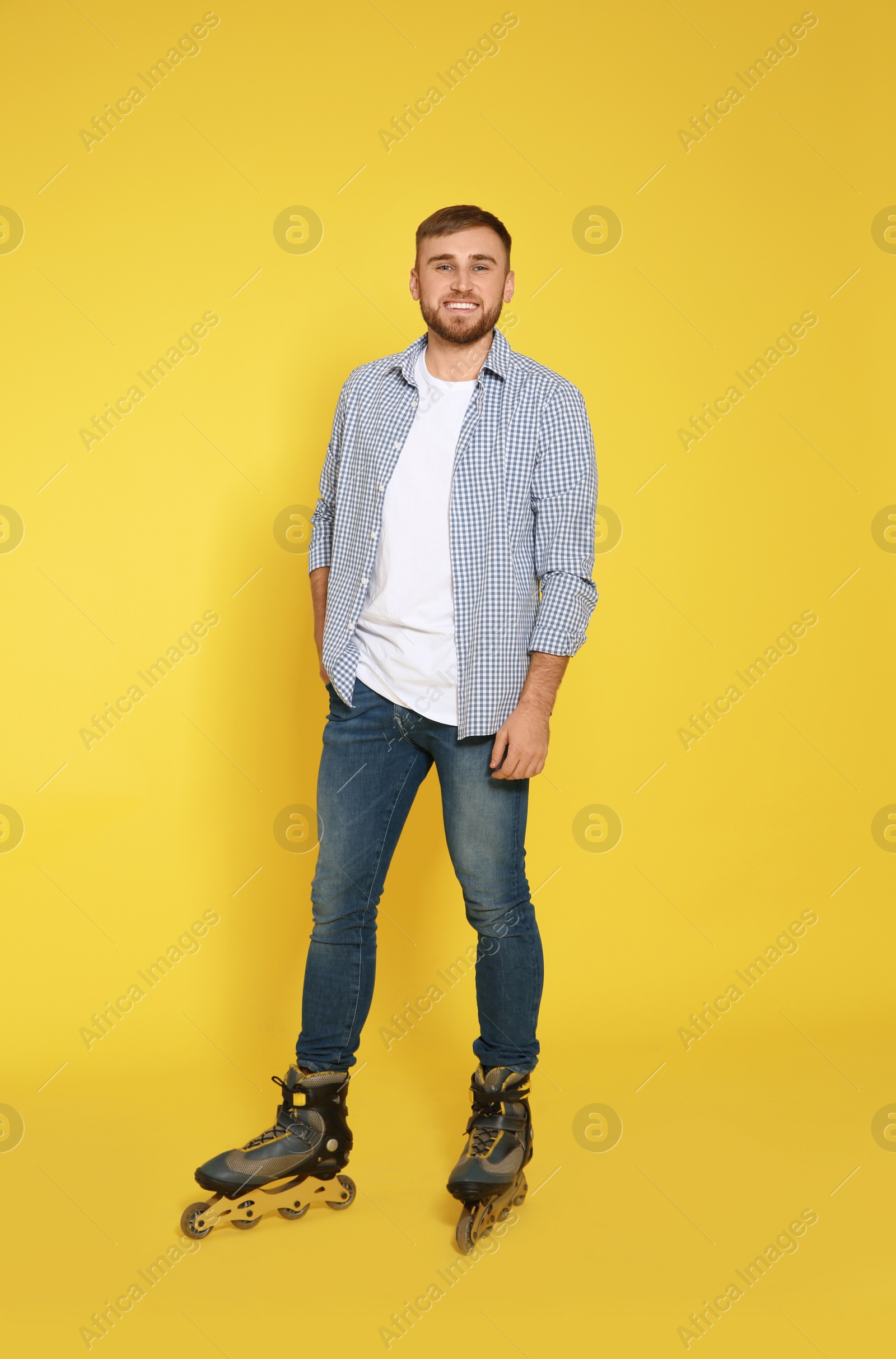 Photo of Full length portrait of young man with inline roller skates on color background