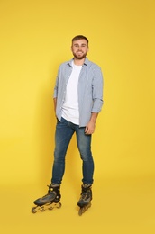 Photo of Full length portrait of young man with inline roller skates on color background