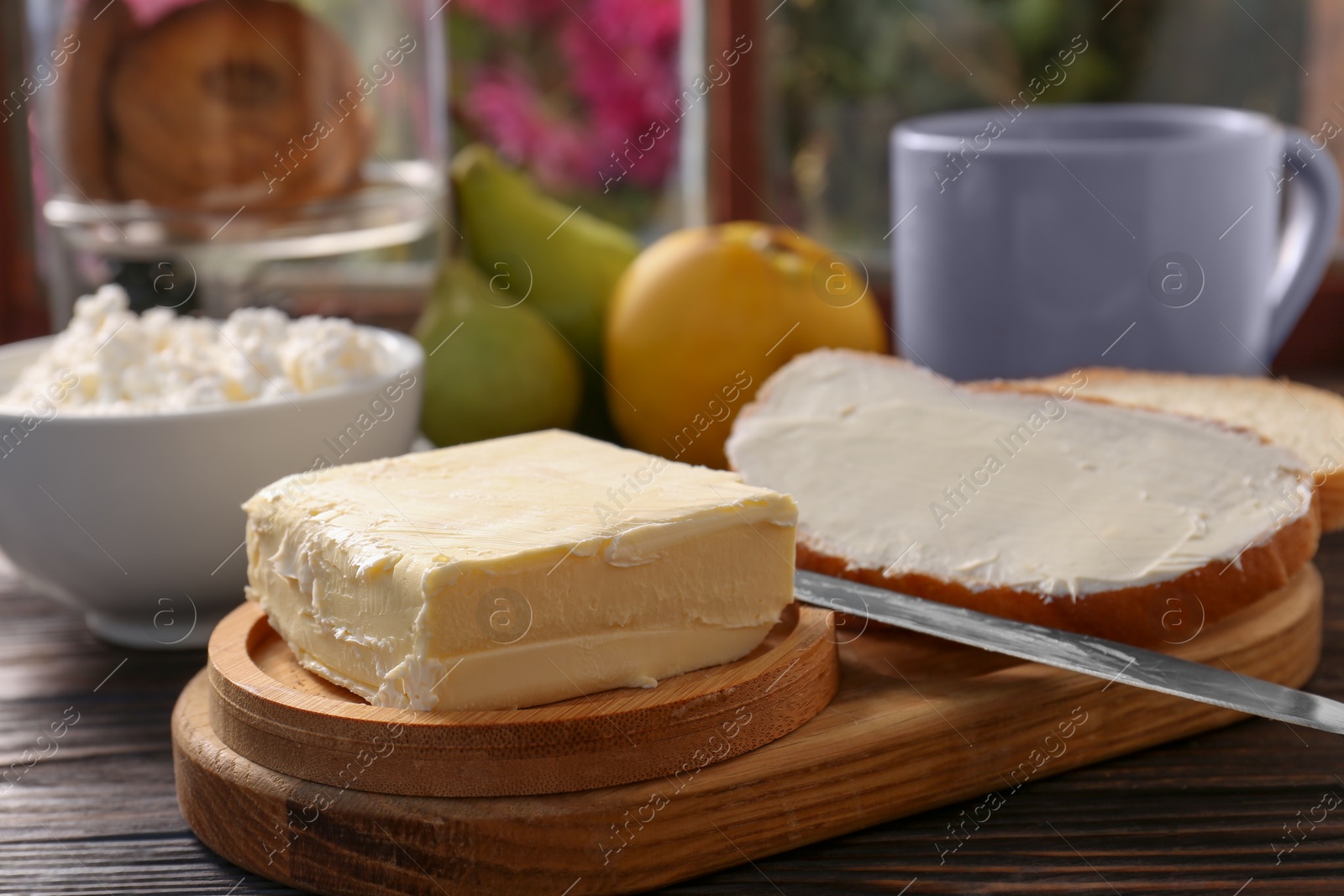 Photo of Tasty homemade butter, bread slices and tea on wooden table