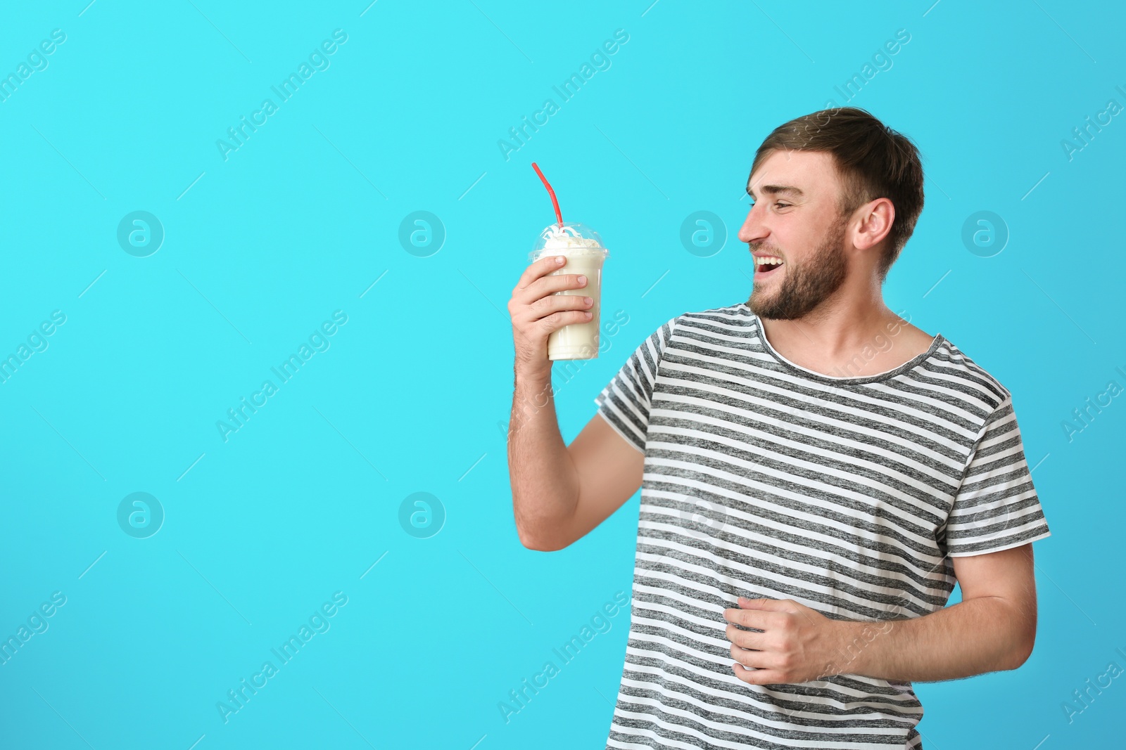 Photo of Young man with cup of delicious milk shake on color background