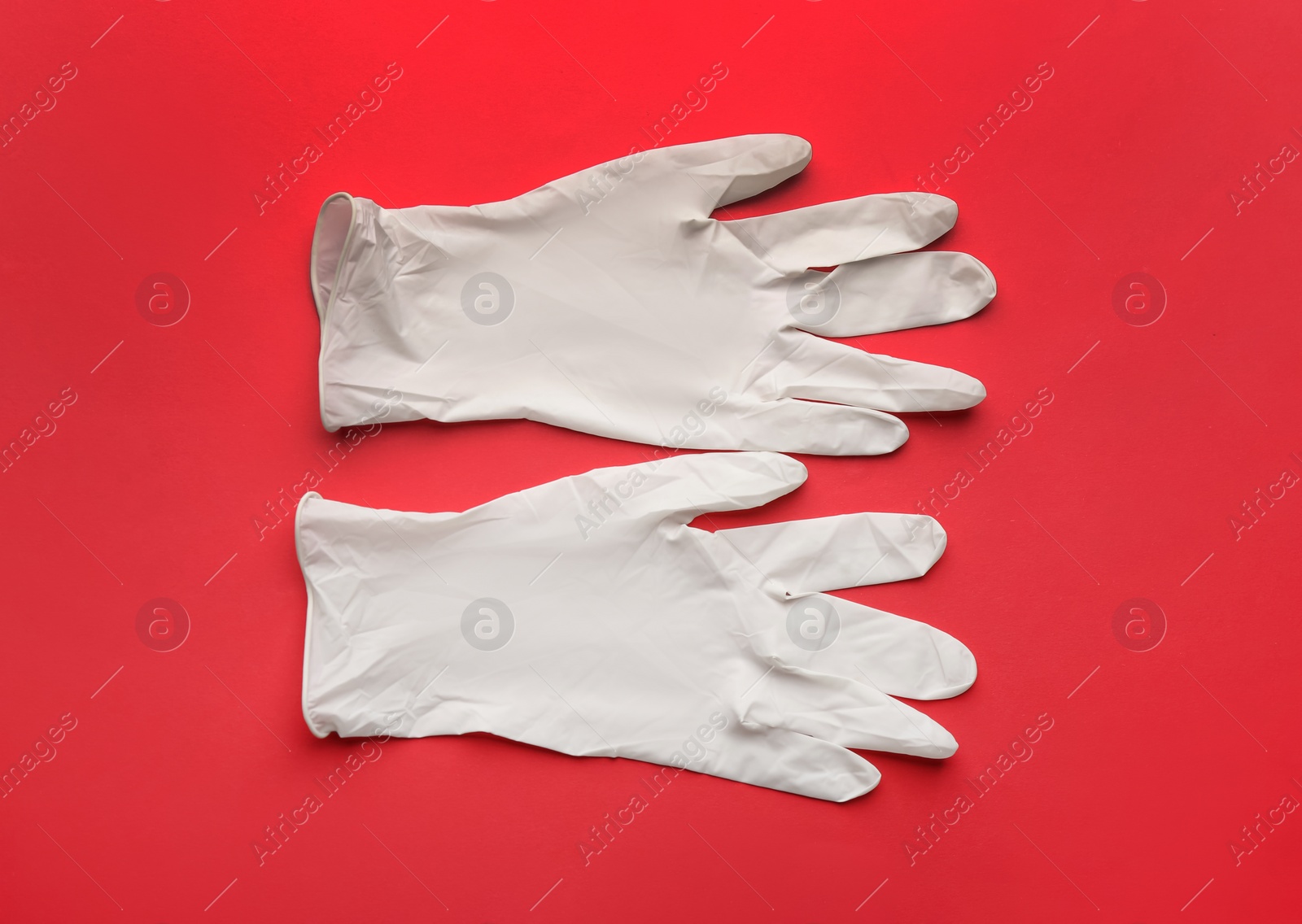 Photo of Pair of medical gloves on red background, flat lay