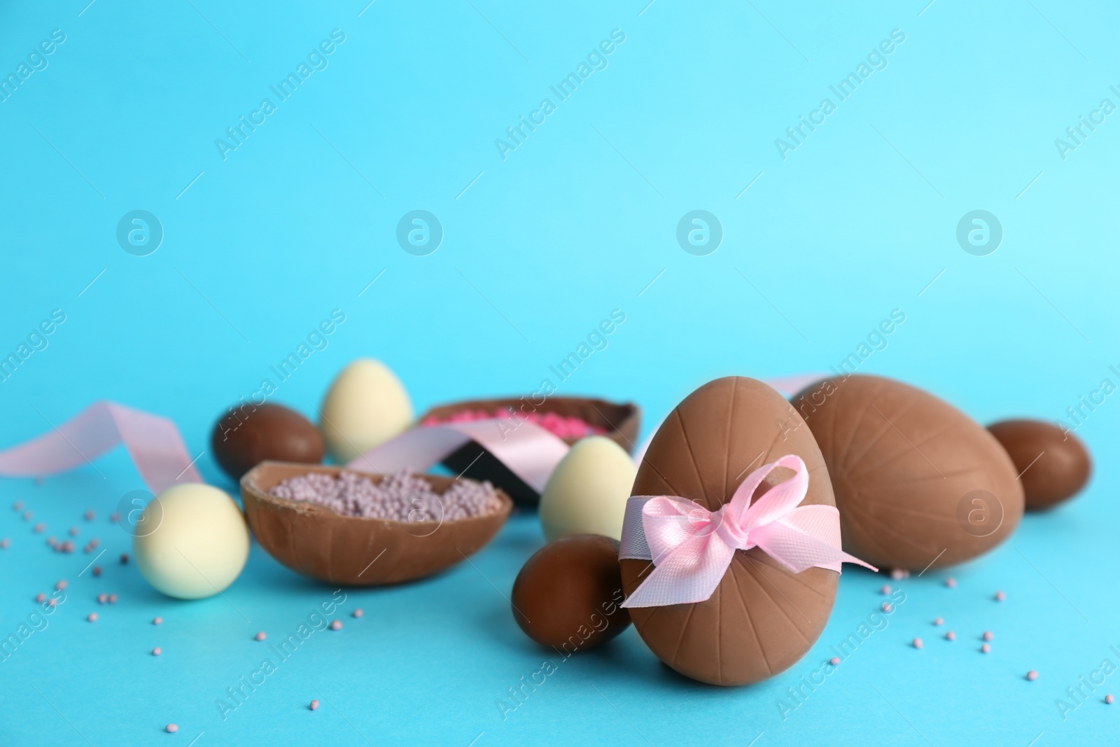 Photo of Sweet chocolate eggs on light blue background. Space for text