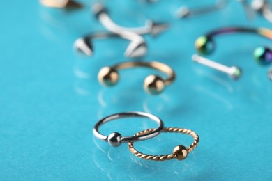 Stylish captive bead rings on light blue background, closeup. Piercing jewelry