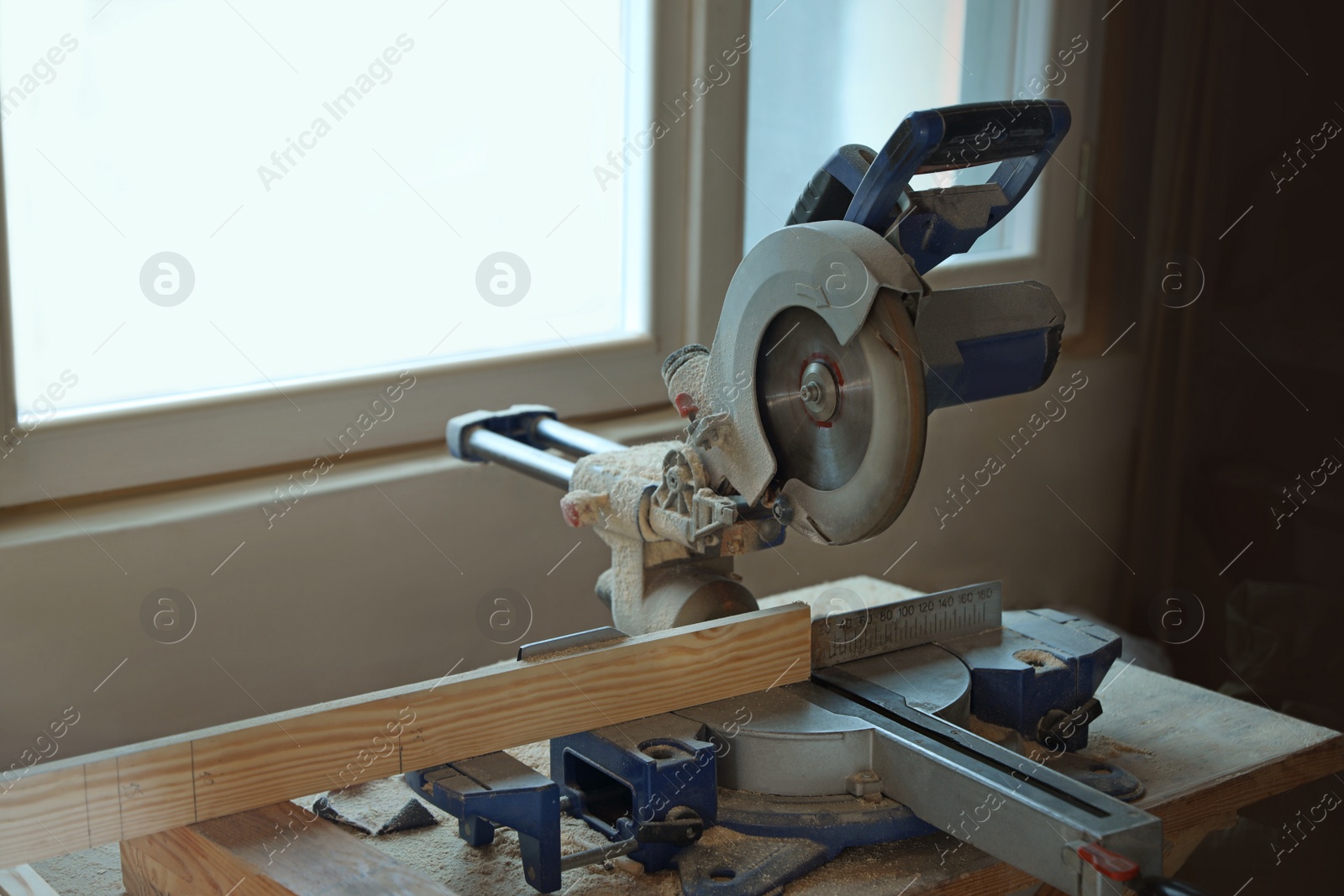 Photo of Carpenter's working place with modern circular saw near window indoors