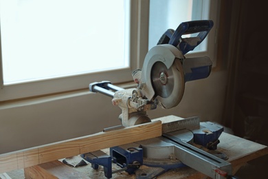 Photo of Carpenter's working place with modern circular saw near window indoors