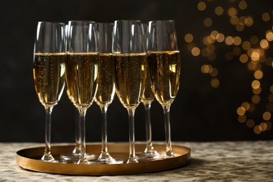 Photo of Tray with glasses of champagne on table against blurred lights. Space for text