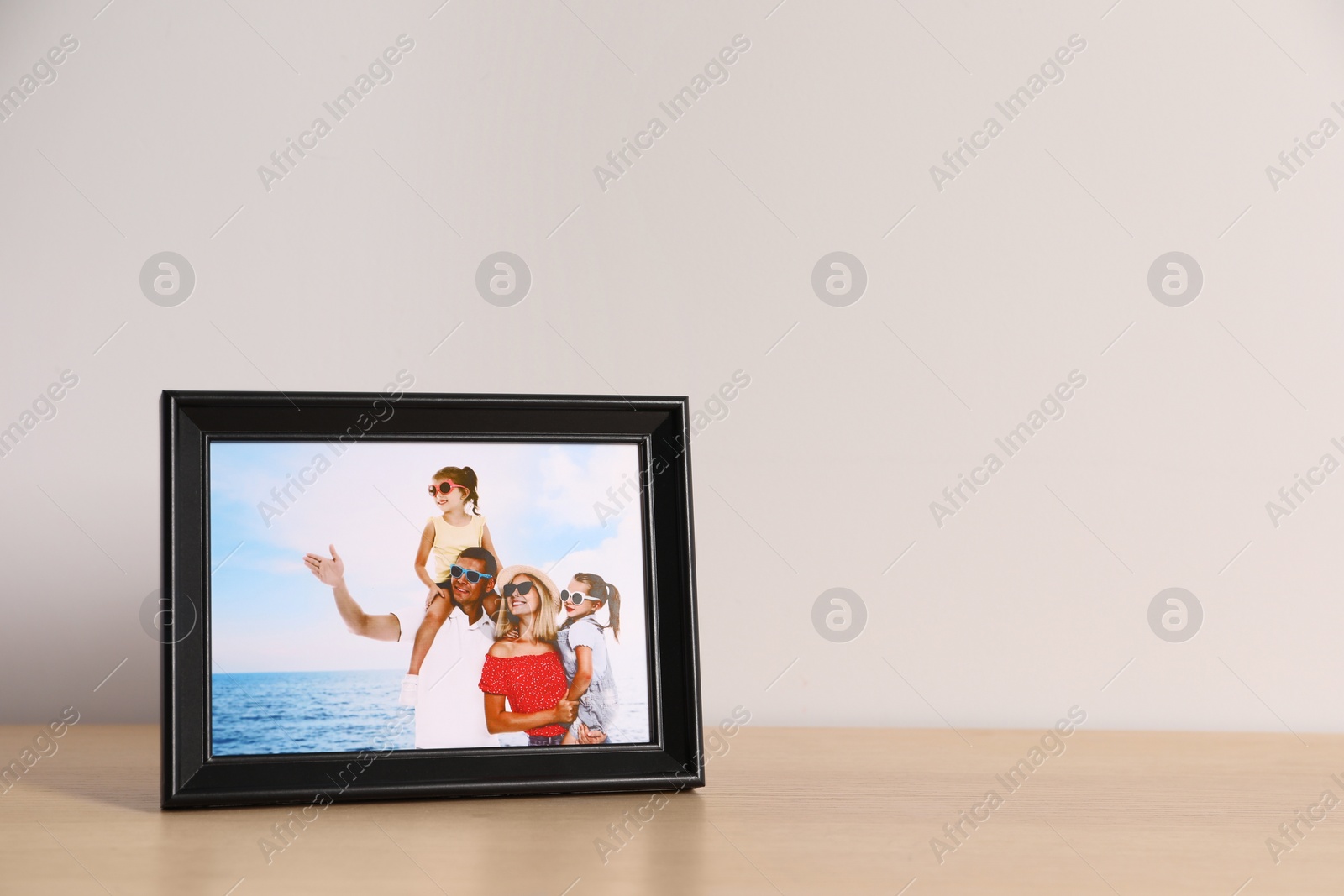 Photo of Frame with family photo on wooden table, space for text