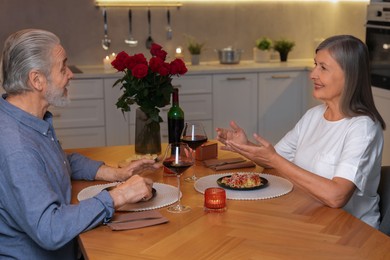 Photo of Affectionate senior couple having romantic dinner at home