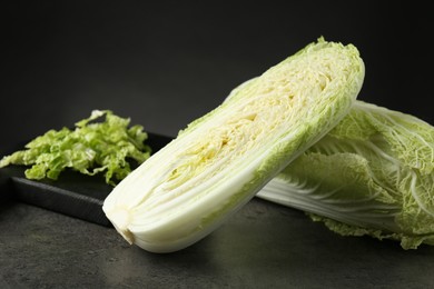 Photo of Whole and cut fresh Chinese cabbages on grey table