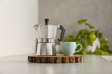 Ceramic cup and moka pot on light countertop in kitchen