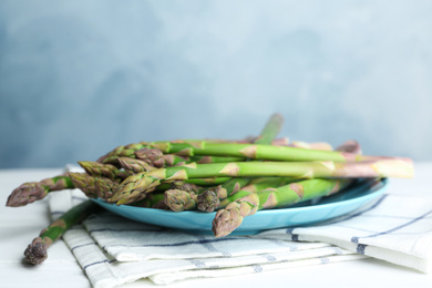 Photo of Fresh raw asparagus on white table, closeup. Space for text