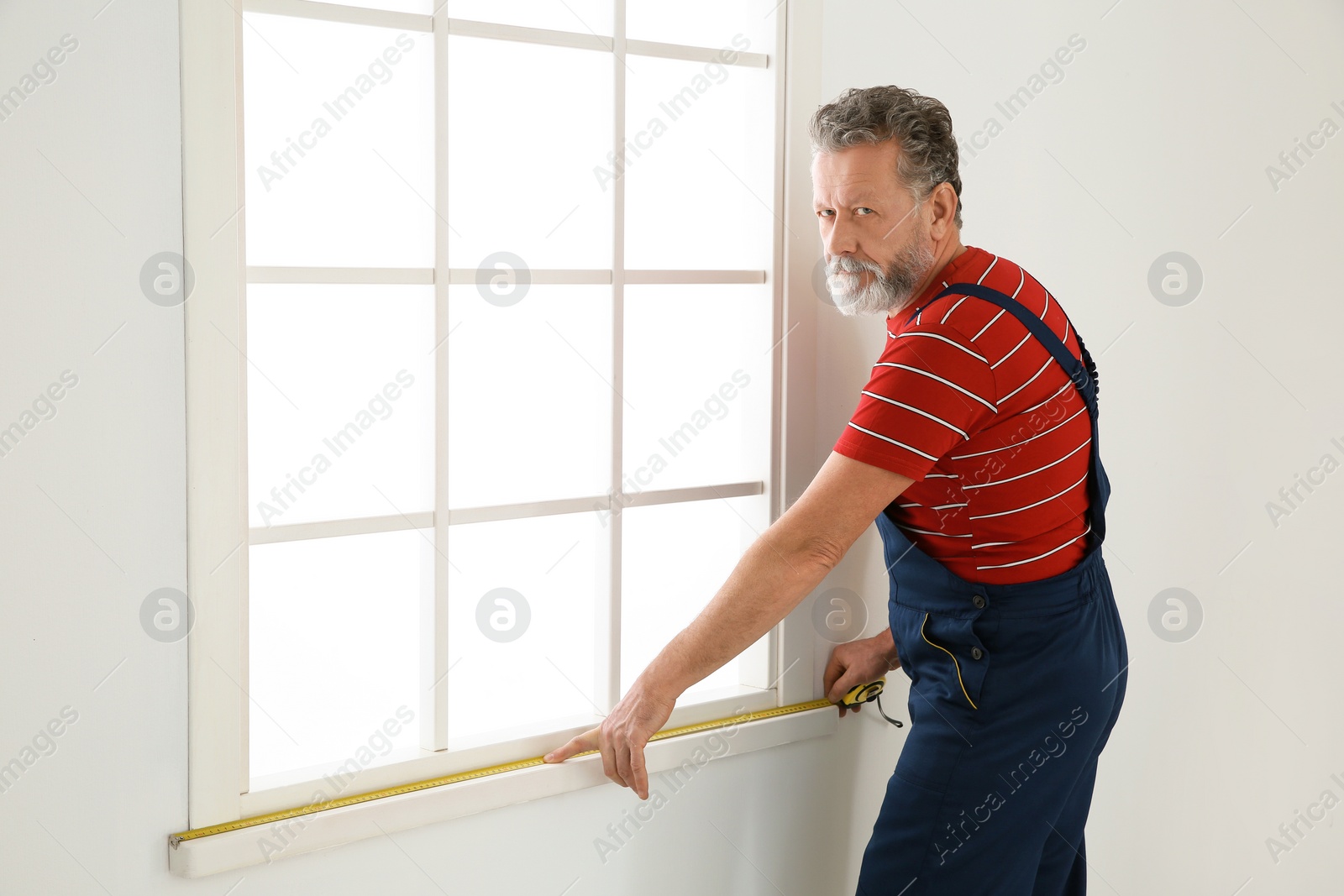 Photo of Service man measuring window for installation indoors