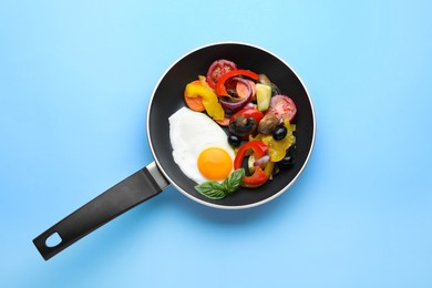 Photo of Tasty fried egg with vegetables in pan on turquoise background, top view