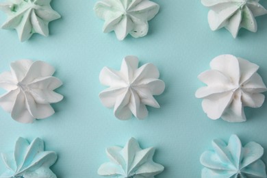 Delicious meringue cookies on light blue background, flat lay