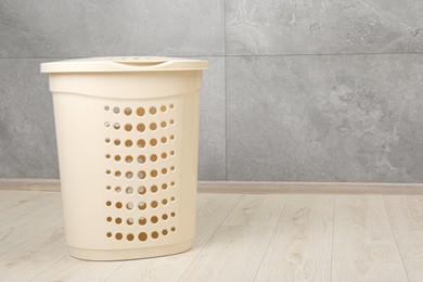 Photo of Empty plastic laundry basket near grey wall. Space for text