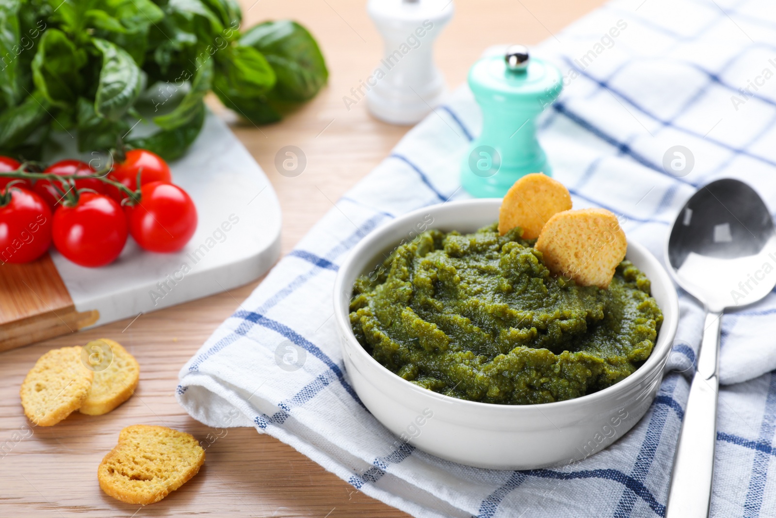 Photo of Bowl with tasty green puree and ingredients on wooden table