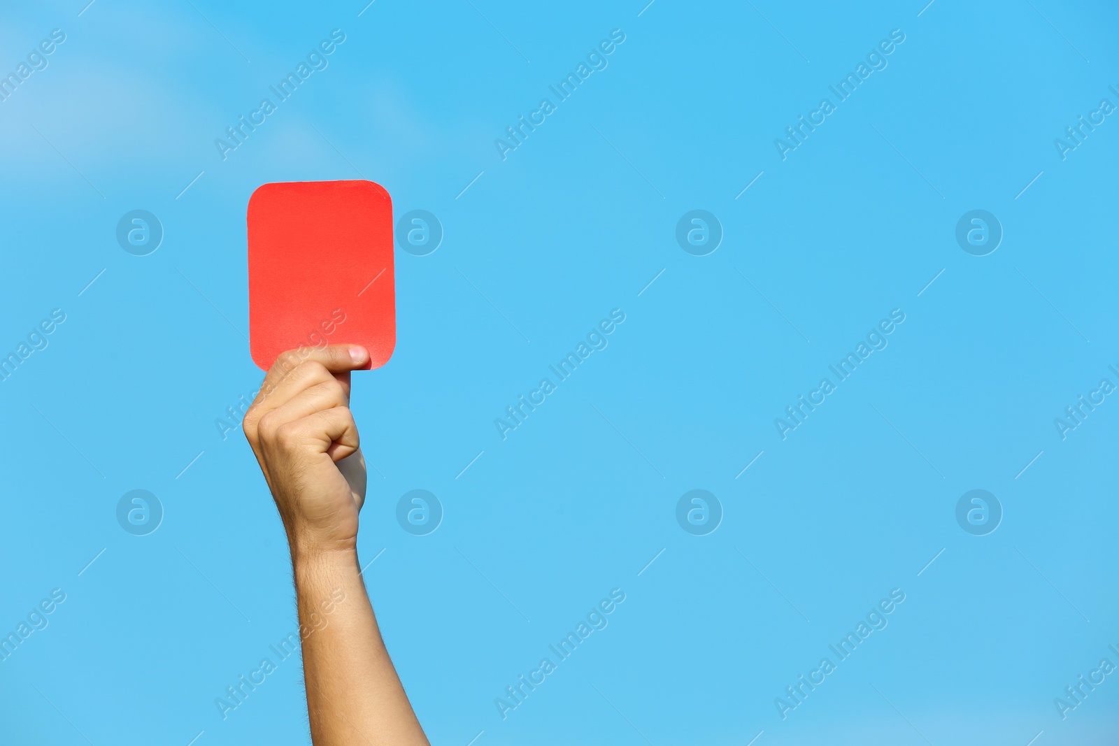 Photo of Football referee showing red card against blue sky, closeup with space for text