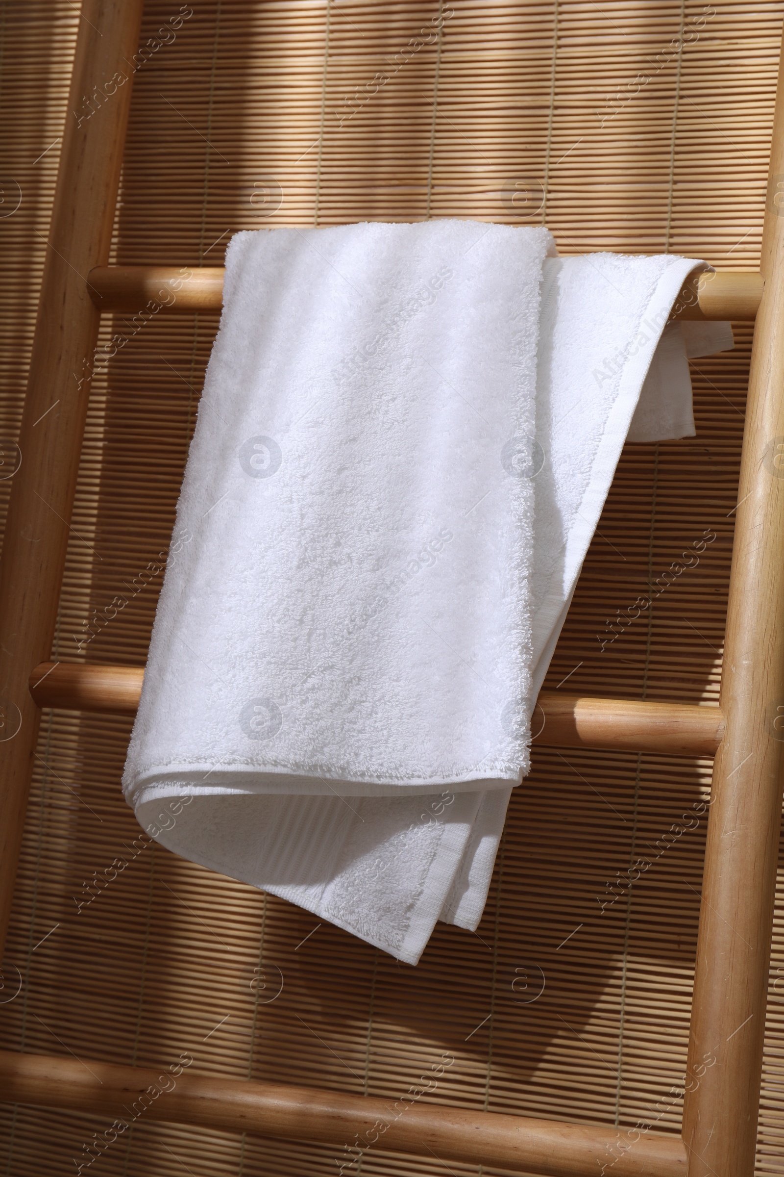 Photo of White terry towel on wooden ladder indoors