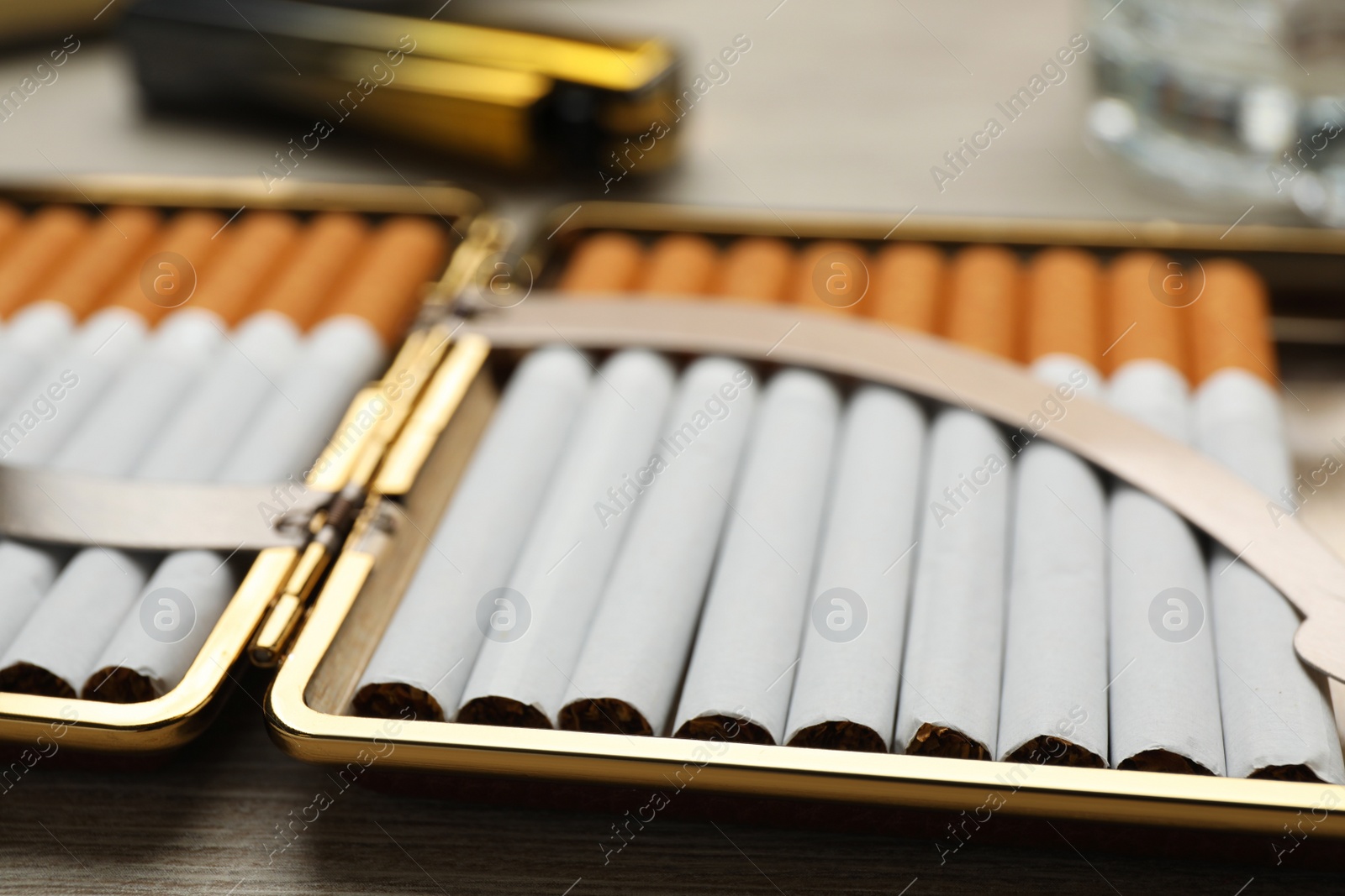 Photo of Open case with tobacco filter cigarettes on wooden table, closeup