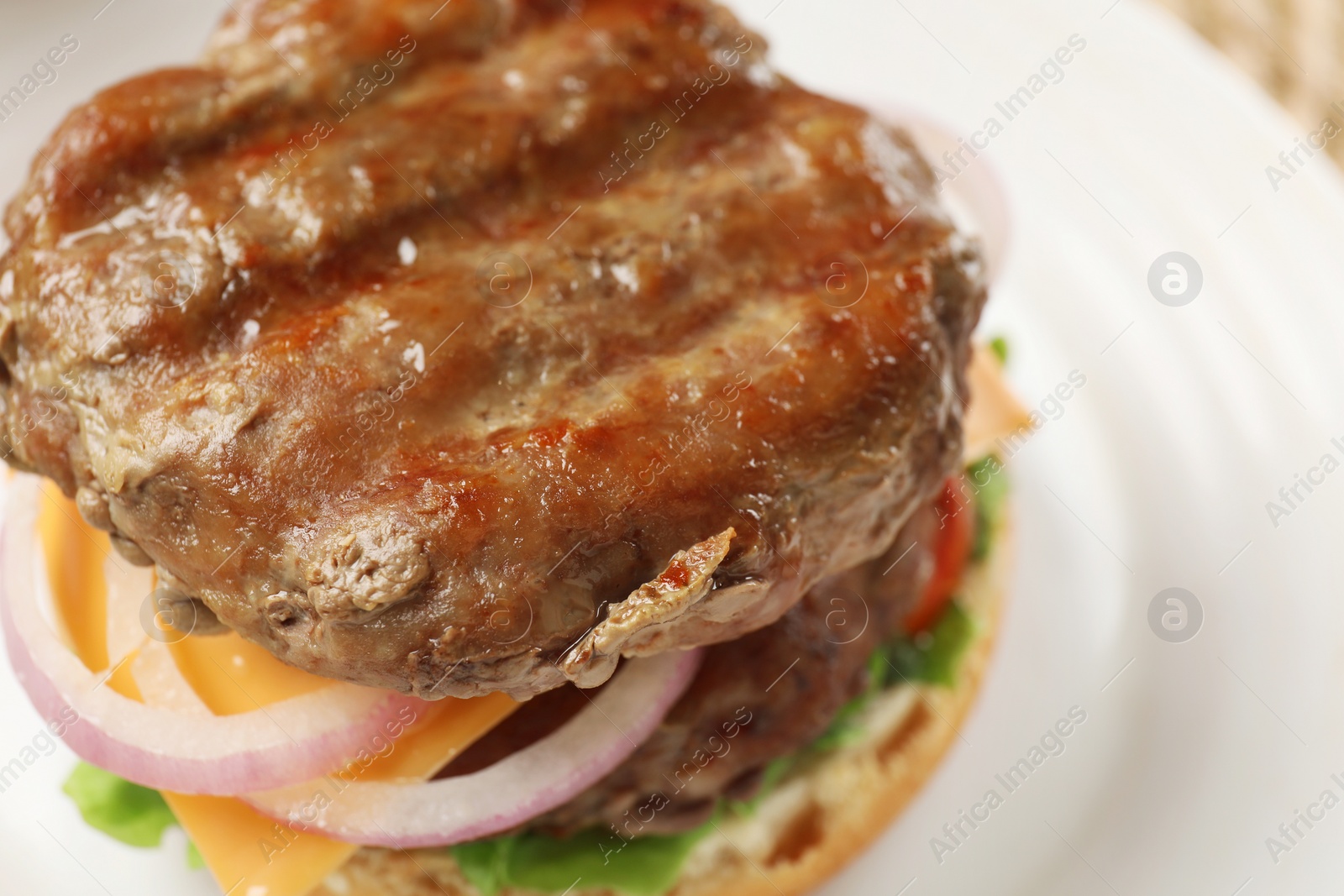 Photo of Tasty hamburger with patties, cheese and vegetables on plate, closeup