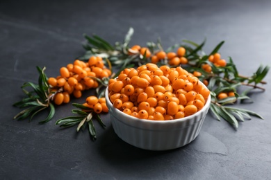 Photo of Fresh ripe sea buckthorn in bowl on black table