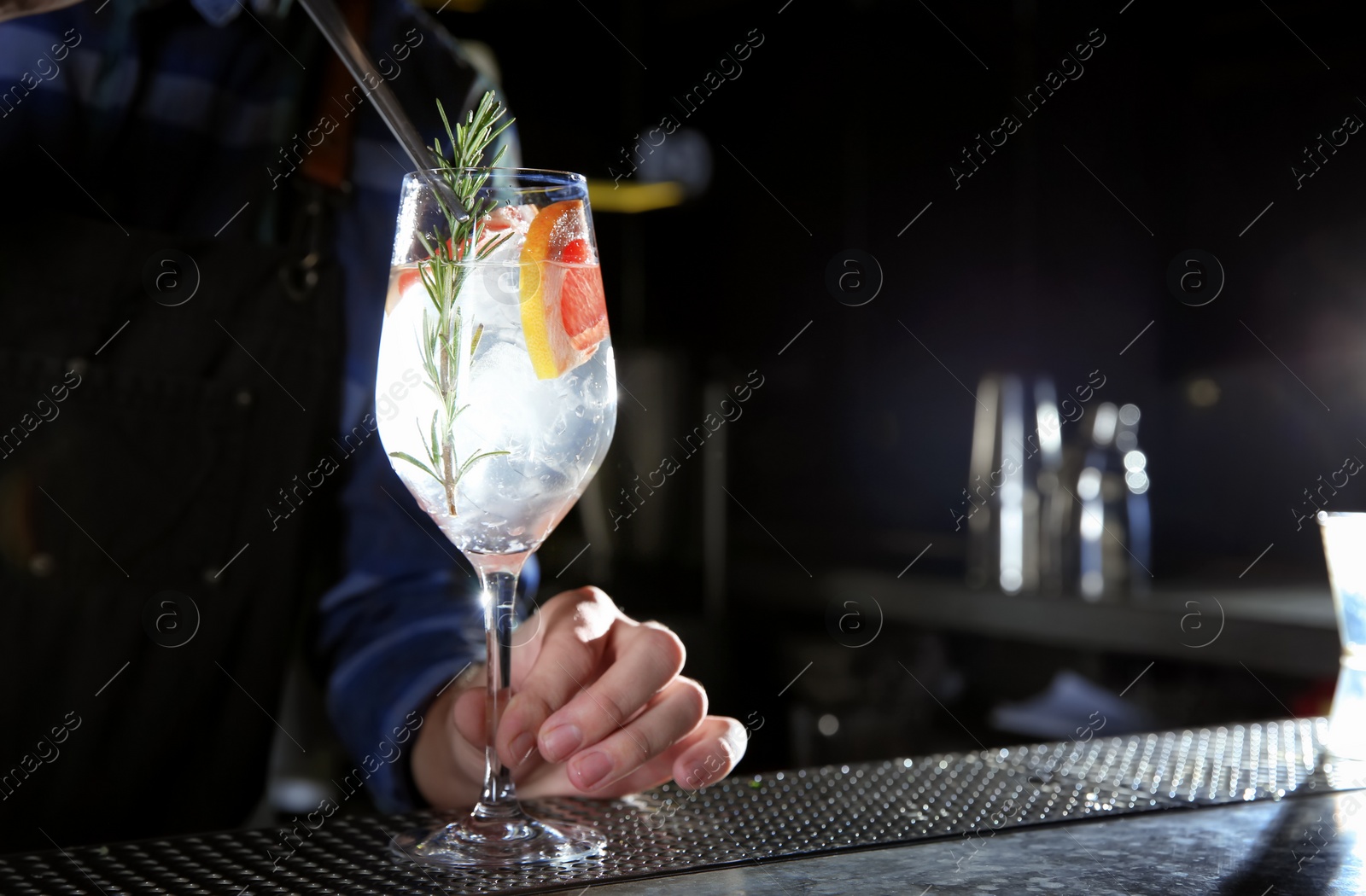 Photo of Barman making grapefruit gin tonic cocktail at counter in pub, closeup. Space for text