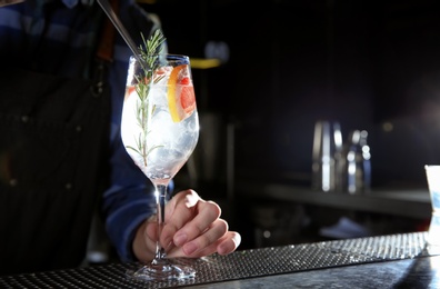 Photo of Barman making grapefruit gin tonic cocktail at counter in pub, closeup. Space for text