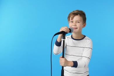 Cute boy with microphone on color background. Space for text