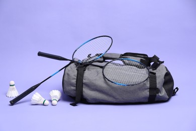 Feather badminton shuttlecocks, rackets and bag on violet background