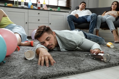 Drunk man sleeping on floor in messy room after party