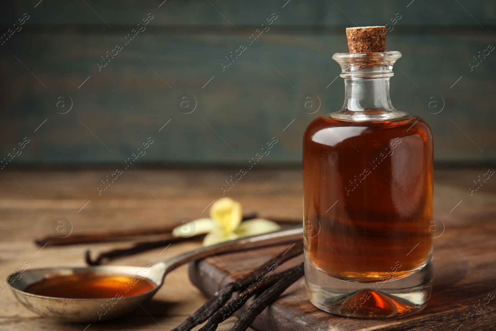 Photo of Aromatic homemade vanilla extract on wooden table, closeup. Space for text