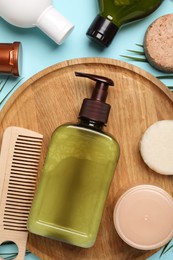 Shampoo bottles, wooden comb, hair mask and solid shampoo bars on turquoise background, flat lay