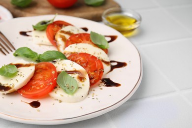 Photo of Delicious Caprese salad with balsamic vinegar on white table, closeup