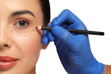 Photo of Doctor with pencil preparing patient for cosmetic surgery operation on white background, closeup