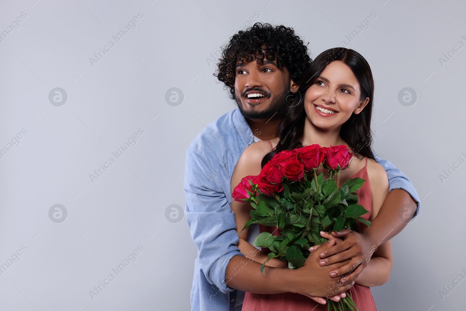 Photo of International dating. Happy couple with bouquet of roses on light grey background, space for text