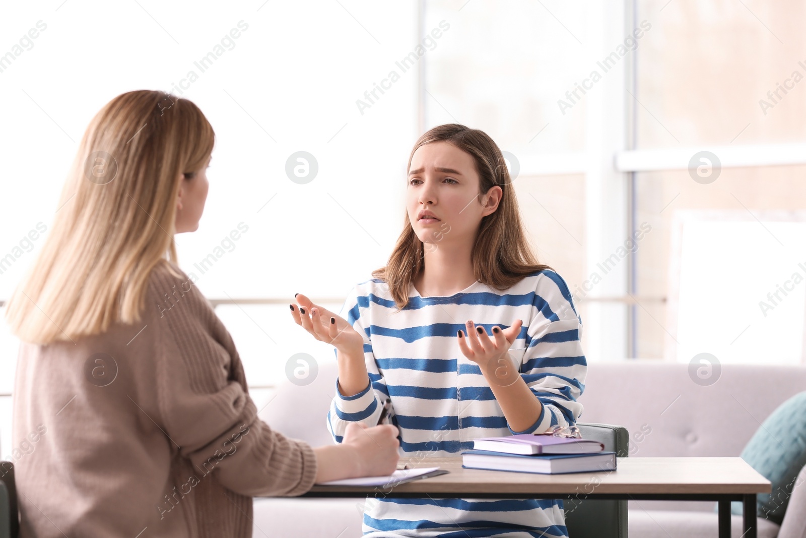 Photo of Young female psychologist working with teenage girl in office