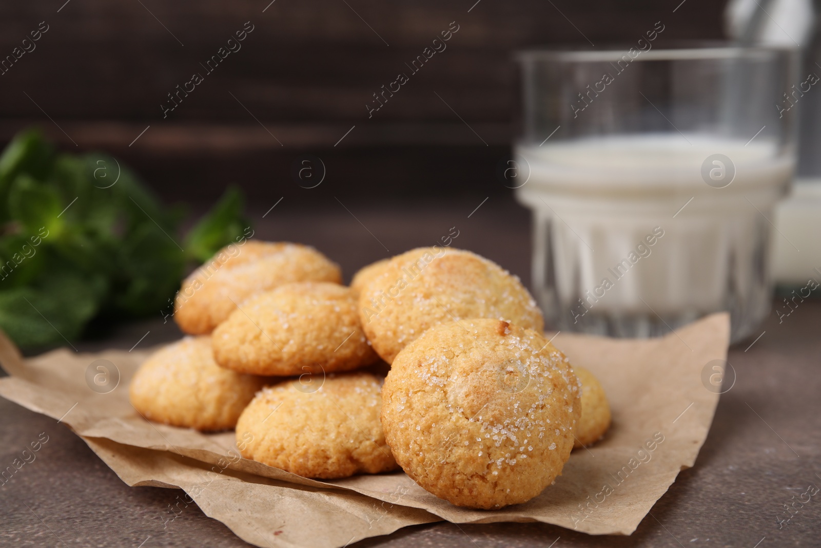 Photo of Tasty sweet sugar cookies and milk on brown table, closeup