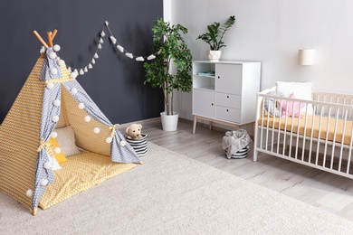 Photo of Cozy baby room interior with play tent and toys