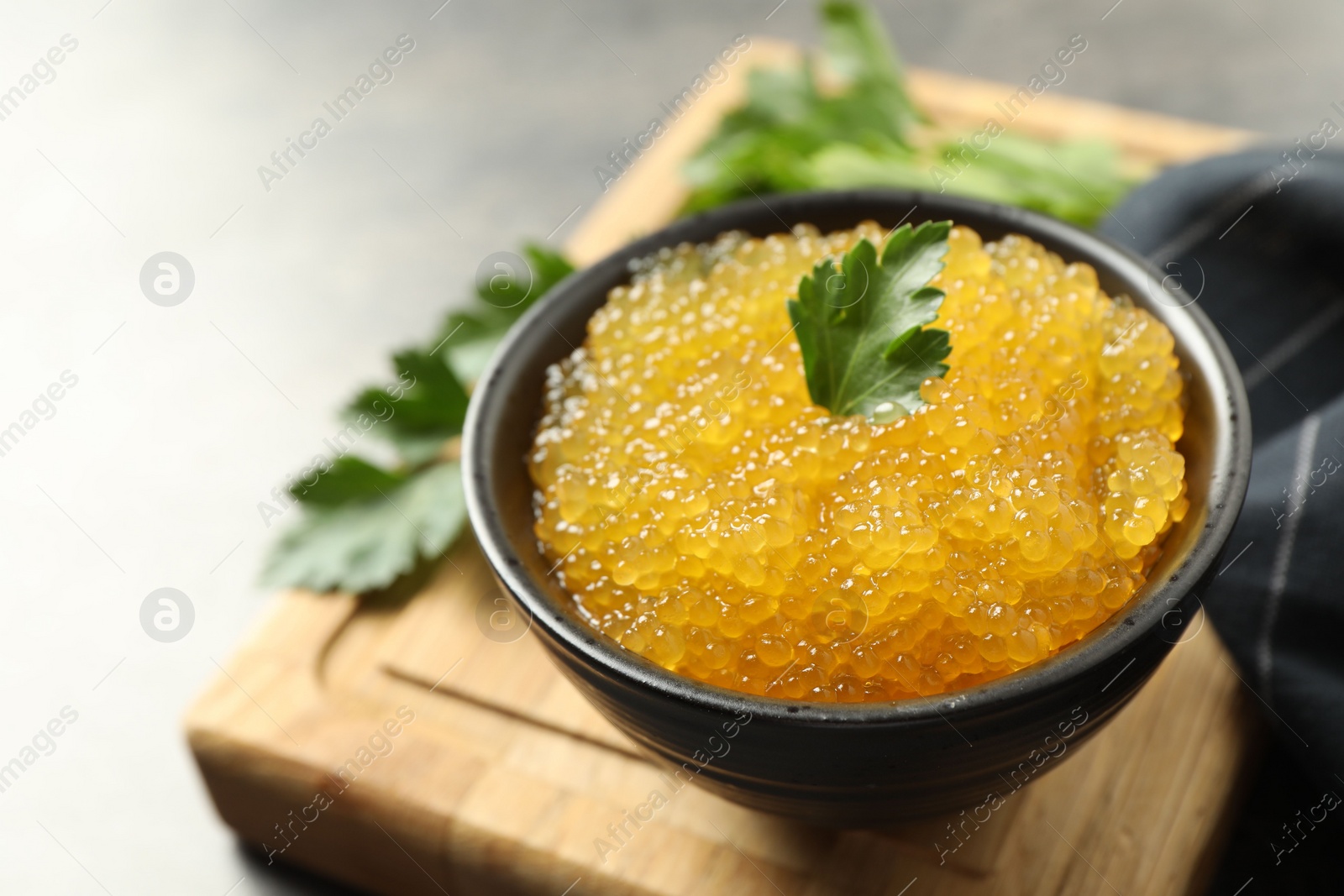 Photo of Fresh pike caviar in bowl and parsley on table, closeup